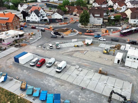 Luftaufnahme der Baustelle für den EDEKA-Markt in Gaildorf mit Blick auf den neu angelegten Kreisverkehr, Lieferwagen, Bagger und Baustellencontainer im städtischen Kontext.