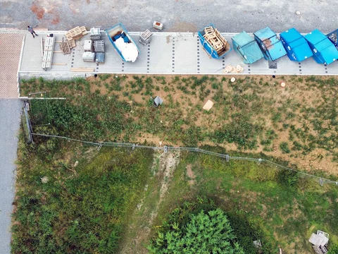 Vertikale Draufsicht auf den Hangbereich der EDEKA-Baustelle in Gaildorf mit ordentlich aufgereihten, verschiedenfarbigen Containern zur Mülltrennung.
