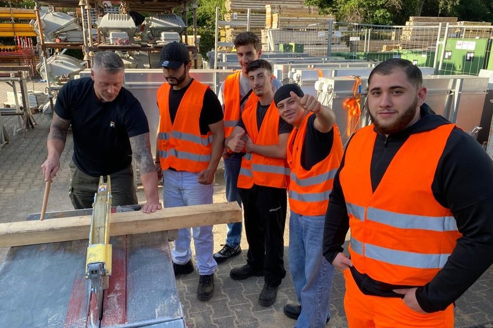 Foto: Gruppe mit Ausbilder beim Sägen von Holz.